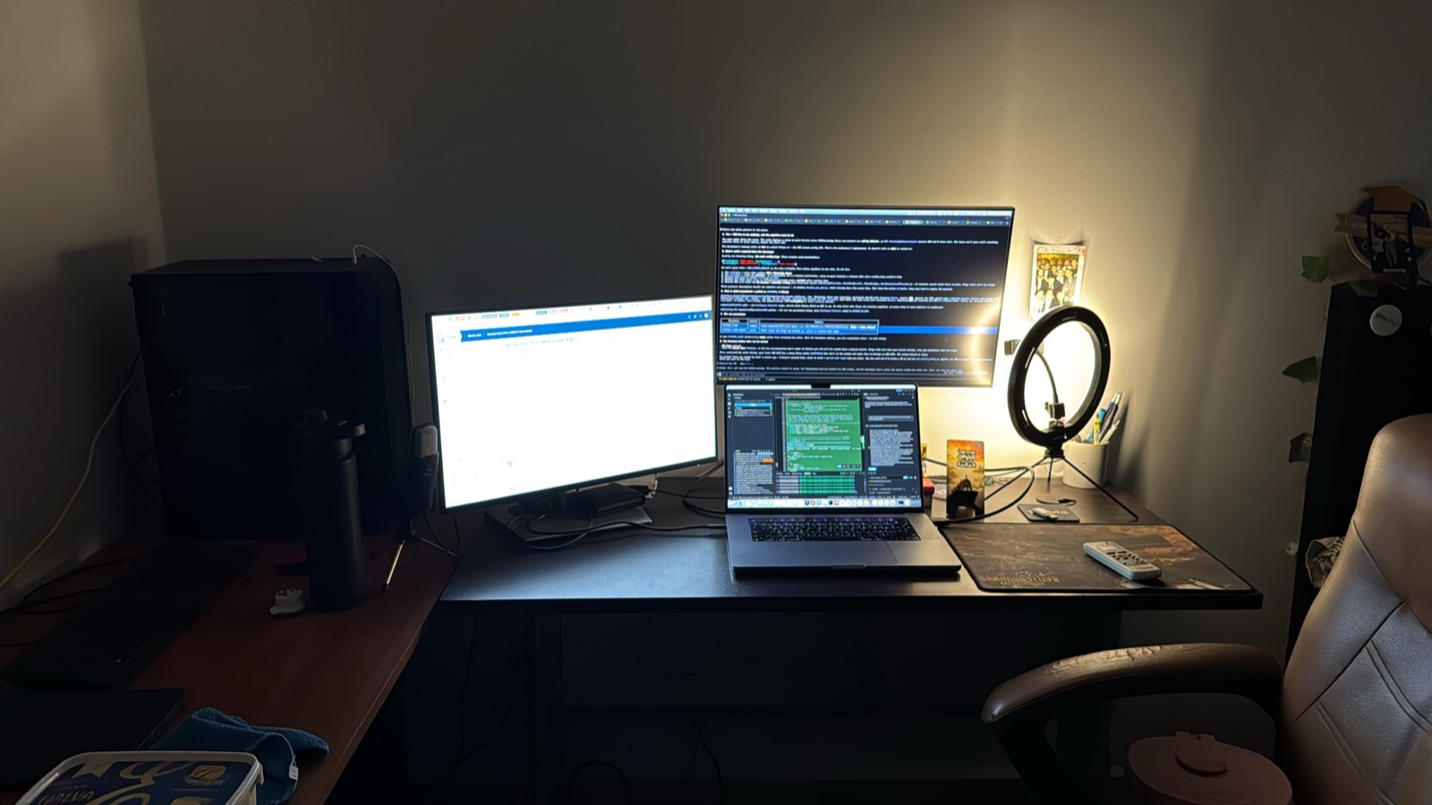 Ahmed’s desk at night: three screens of code, a laptop and a ring light